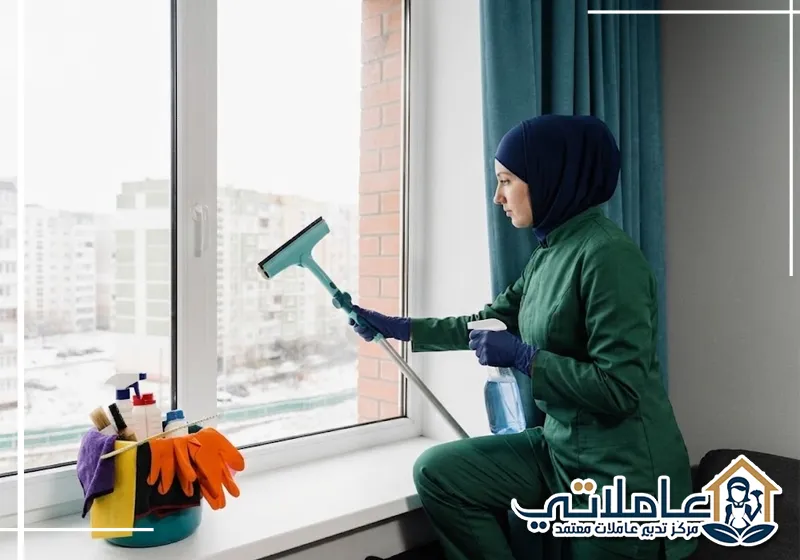 عاملة منزلية من عاملاتي تقوم بتنظيف زجاج النوافذ داخل منزل عصري.