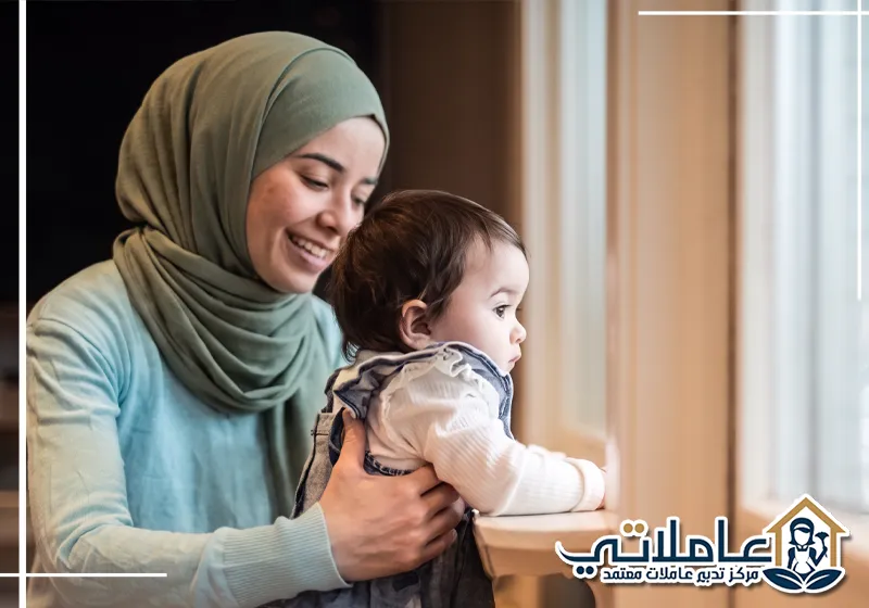 مربية أطفال تحمل طفلة وتعتني بها داخل المنزل.
