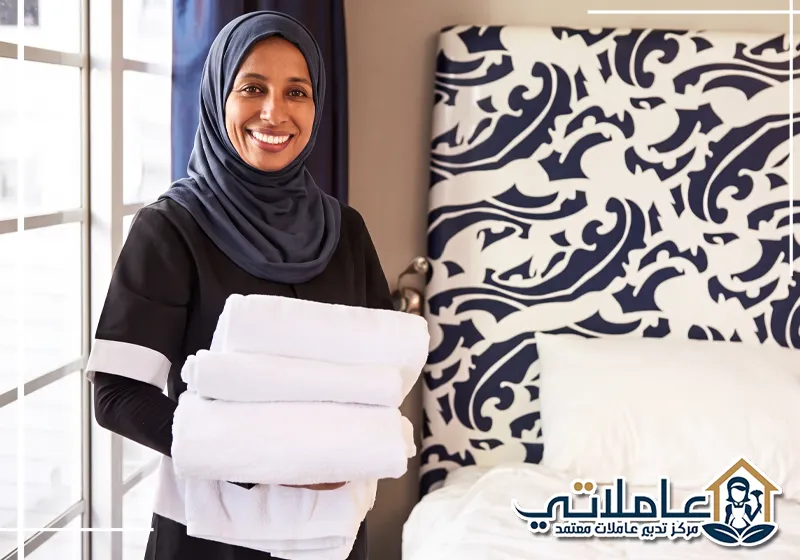 عاملة منزلية تحمل المناشف النظيفة داخل غرفة النوم.